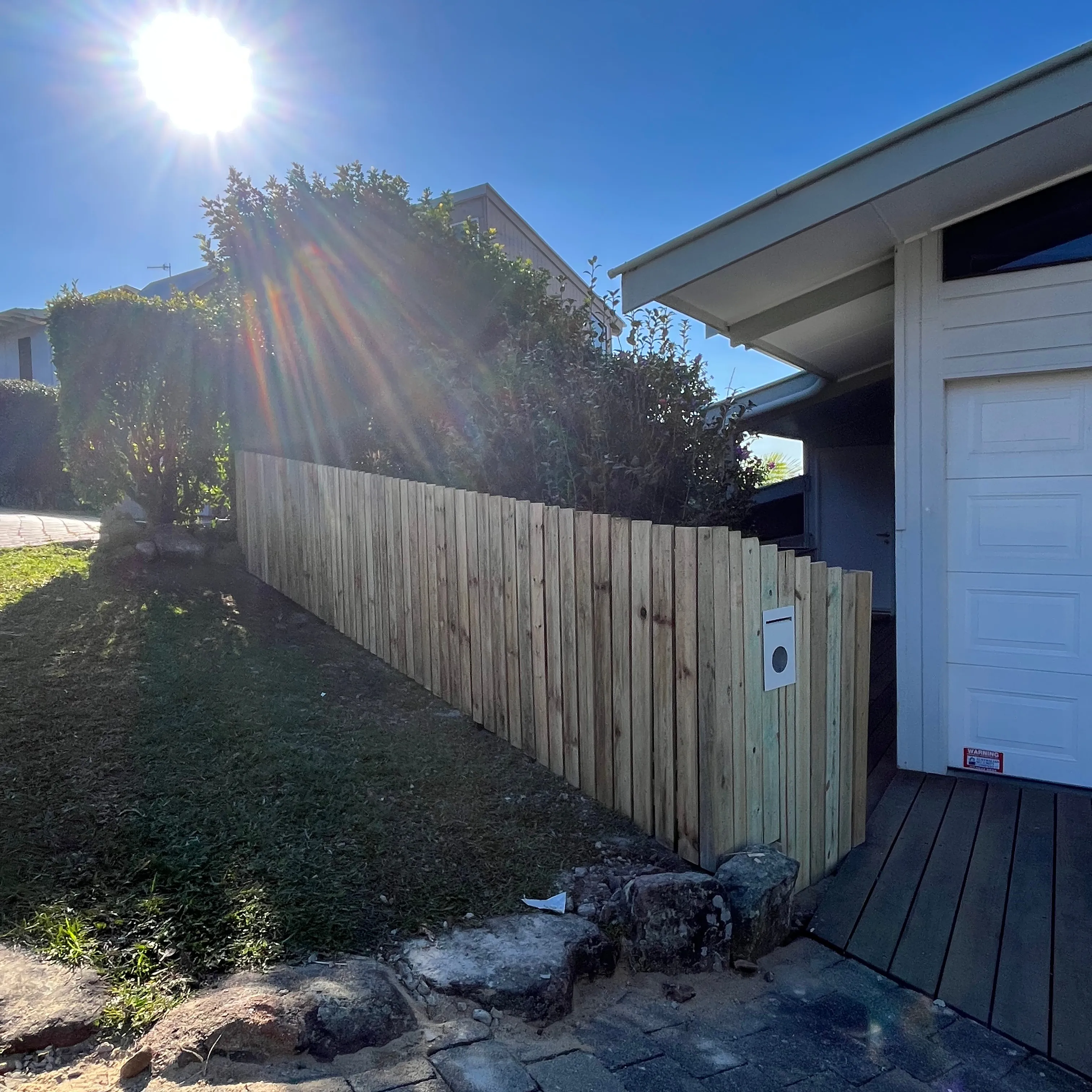 Timber paling fence following a sloped yard beside a house