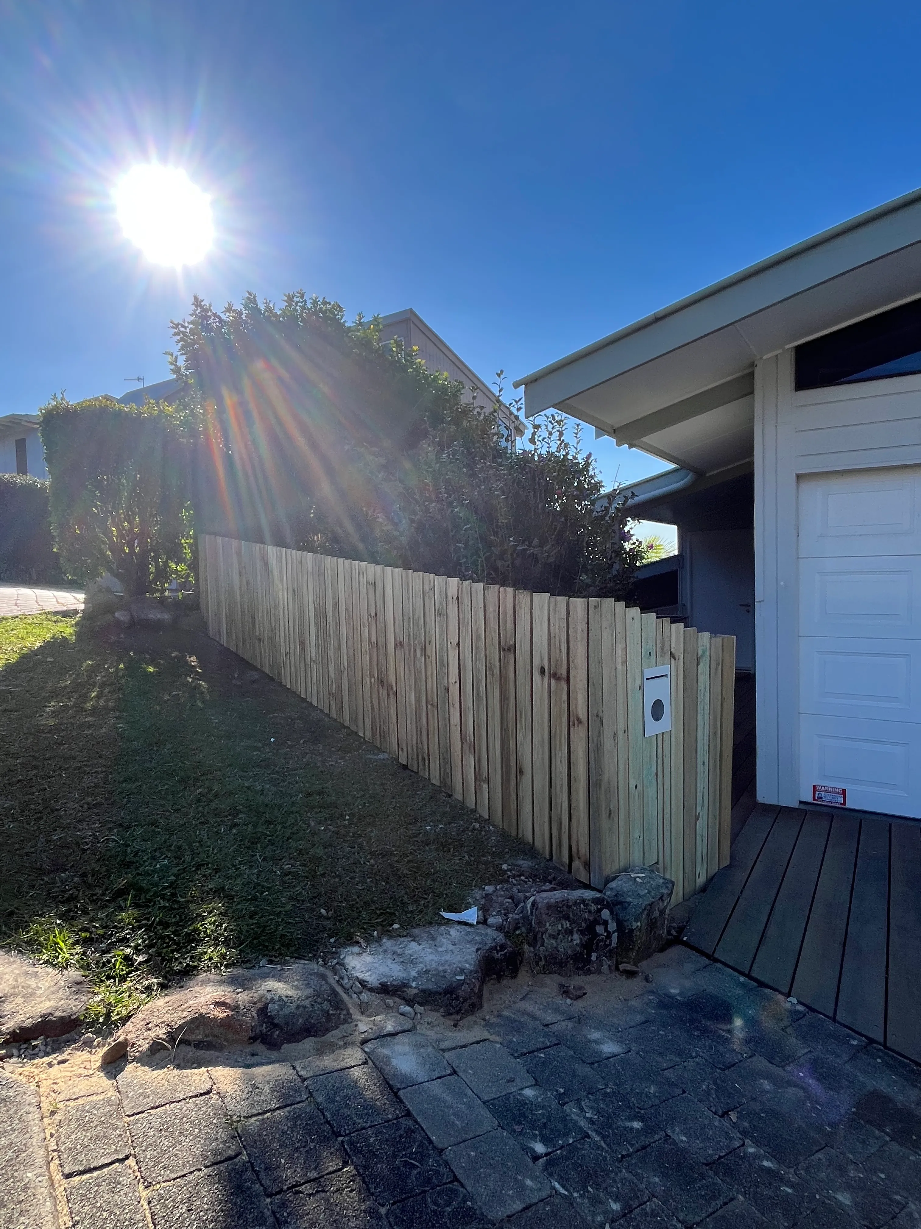 Timber paling fence following a sloped yard beside a house
